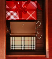 Shot of an open draw with a present wrapped in Burberry Check wrapping paper and an open Burberry Check bag