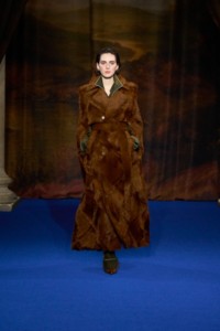 Lottie Morris wearing Check patchwork shearling trench cape in caramel brown, foliage print silk poplin pyjama shirt and trousers in moat green and leather Fringe pumps in knot brown.