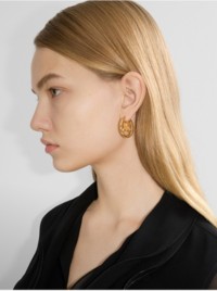 Modelo que luce pendientes de aro con EKD color dorado