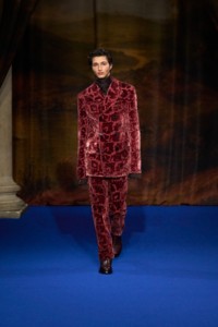 Rubuen Bilan-Carroll wearing vine velvet jacquard tailored jacket and trousers in dragon red, silk jacquard shirt in hawk brown with leather boots in mahogany red.