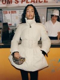 Aufnahme eines Models in mittellanger wattierter Jacke vor einem Fish-and-Chips-Stand