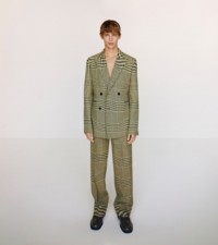 Model wearing the Prince of Wales check jacquard tailored jacket and trousers in ivy, with shiny leather Barbed loafers in poison.