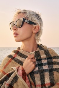 Iris Law modelling in Burberry Sunglasses while wrapped in a Check Towel on a beach