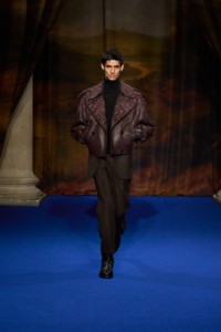 Nakul Bhardwaj wearing floral embroidered leather trench jacket in berry purple, cashmere rollneck sweater in walnut brown, wool tailored trousers in bark brown and leather boots in black.