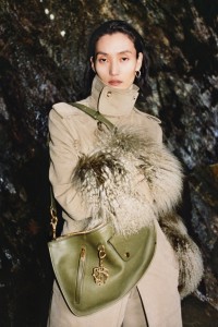 Modella con un trench in moleskin con finiture in shearling e una borsa Shield Twin