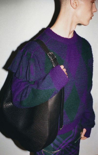 Campanha Inverno 2023 da Burberry apresentando modelo usando um suéter de lã com estampa Argyle em Royal e uma bolsa de ombro Chess de tamanho extragrande em preto