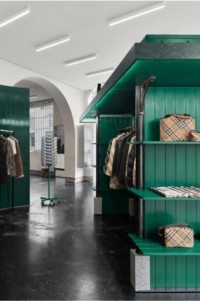 Window display of Burberry products hanging on a clothing rack and placed on green shelves