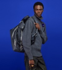 Model wearing Cashmere Turtleneck Sweater in Charcoal paired with Denim Trousers holding Burberry Check Rocking Horse Bag