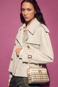 Shot of model wearing cropped Burberry Trench Coat, holding Check Vanity Bag​ in colour Archive beige/briar brown