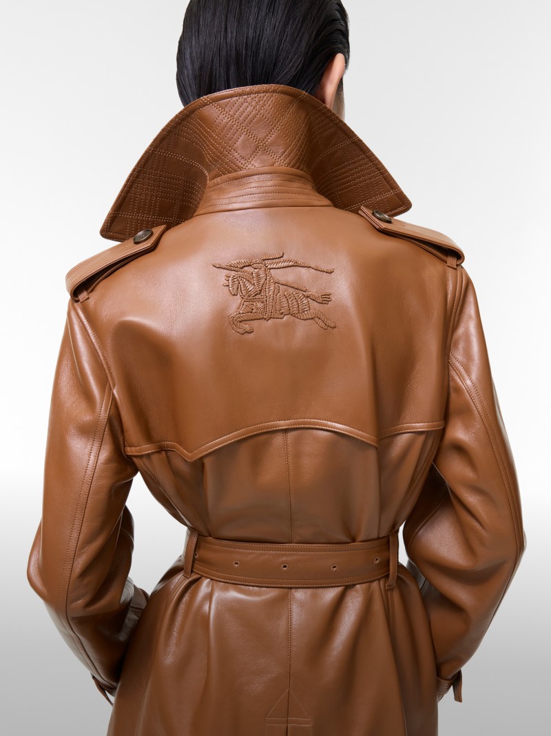Back view of a person wearing a brown leather Burberry trench coat with a raised collar and an embroidered Equestrian Knight Design motif.