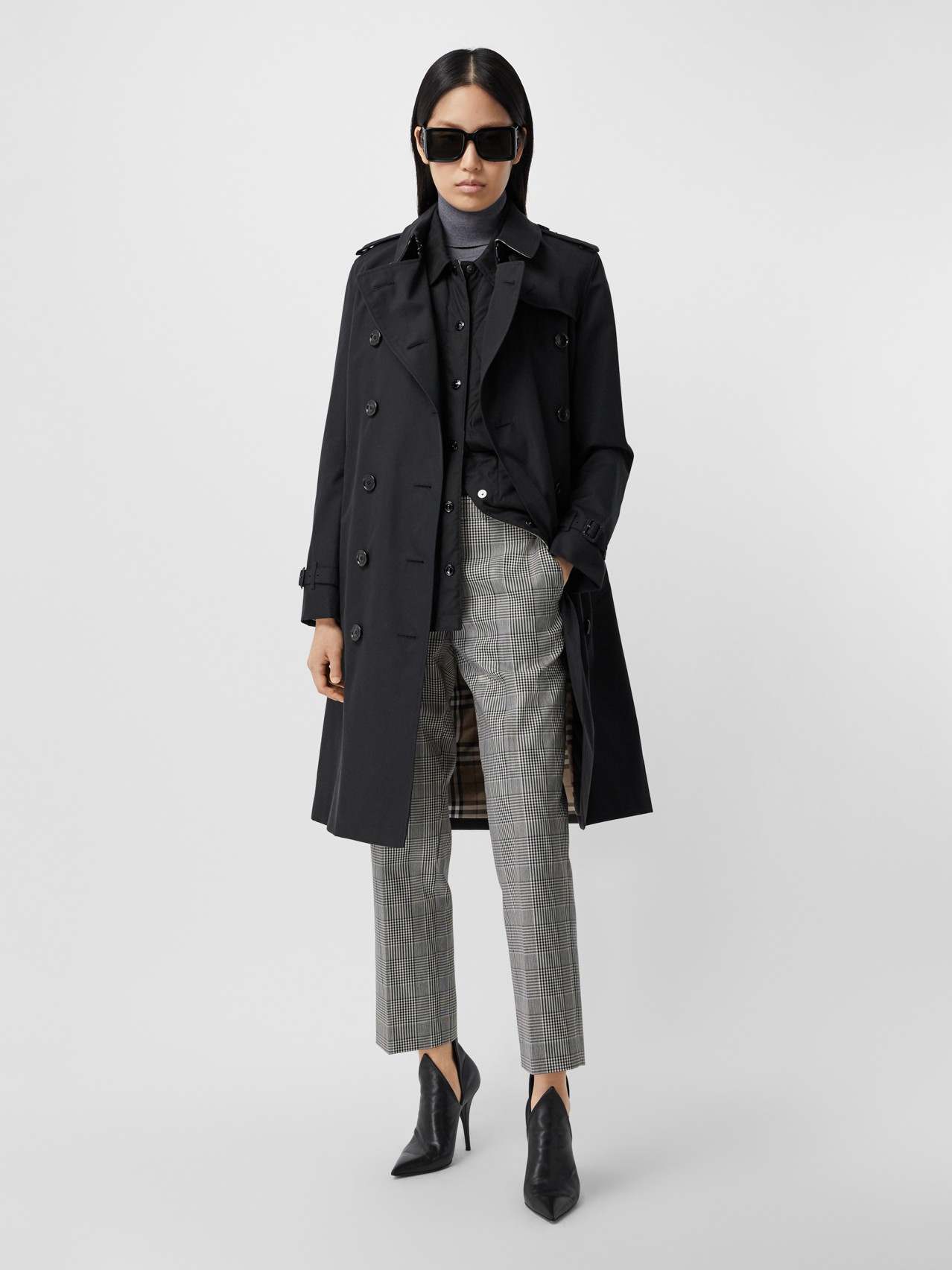Woman in black trench coat with plaid trousers