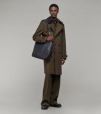 Modello che indossa un trench in tweed, pantaloni sartoriali e una tote Shield Twin piccola