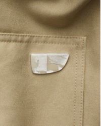 Primo piano delle tasche a patta con bottoni a pressione e dell'Equestrian Knight Design sul parka Burberry