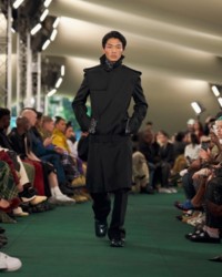 Model wearing trench coat with tailored trousers.