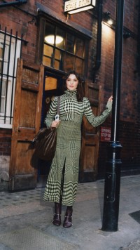 Model in einem Oberteil aus einer Wollmischung in einem Jacquard-gewebten Prince of Wales-Karomuster in den Farben Sherbet und Ivy mit hohem Kragen