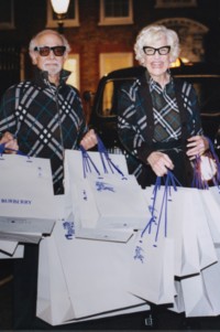 Foto de casal usando jaquetas em xadrez Burberry Check e segurando bolsas de compra