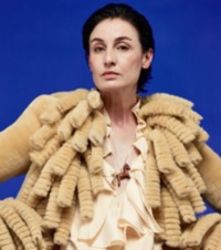 Modelo usando uma jaqueta de shearling com franjas em Hay, com uma blusa de seda franzida em Pelican