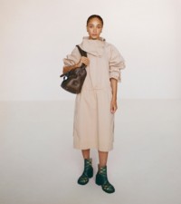 Modella che indossa abito dotato di colletto con bottoni a pressione in flax e tote Shield piccola con EKD in military.