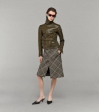 Modella che indossa una giacca in pelle con gonna Burberry Check e mule in pelle