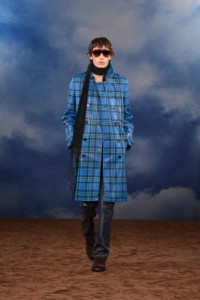 Burberry SS26 Show model Noah Bates wearing a Check coated trench coat and a black Knitted scarf