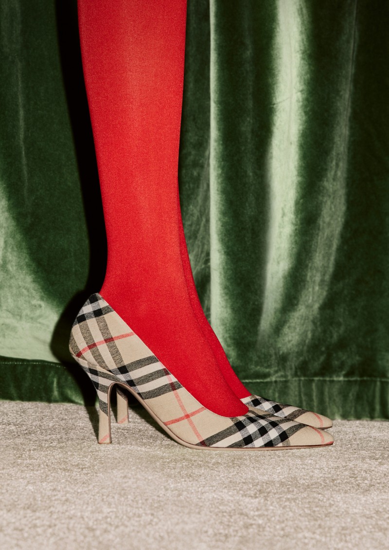 Burberry Festive Campaign featuring a model wearing check heeled Dame pumps and red tights. 