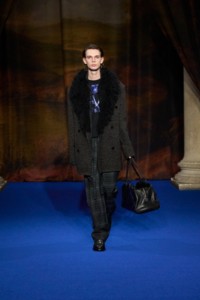 Eddy Earl faux fur wool cashmere blend coat in chess black and cobble grey, wool blend T-shirt and trousers in grit grey, leather Ledger boots in anchor grey, paired with bowling bag in storm blue.