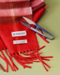 Bufanda a cuadros Burberry Check de color rojo con unas tijeras encima