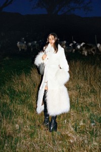 Modelo que luce un trench coat en lana, seda y pana con detalles en pelo sintético y botas altas Pillar en piel color negro