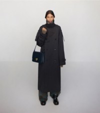 Model in Trenchcoat und mit der Tasche „Shield Case“