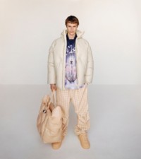 Modelo usando um casaco acolchoado de couro com EKD em marfim, com calças de malha em pied-de-poule com estampa de dentes-de-leão.