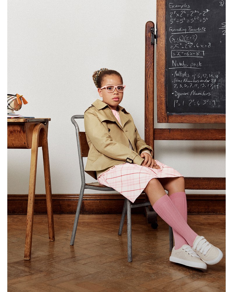 Shot of model wearing Girls' Cotton Trench Jacket in colour Sand Beige, over a Check Cotton Dress in colour Flora pink