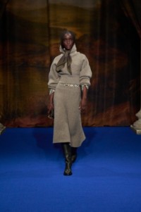 Maty Fall wearing the wool sweater and wool skirt in beige melange, check silk pyjama shirt in linden beige, paired with leather cavalier boots in anchor grey and check cashmere silk scarf in truffle brown. 