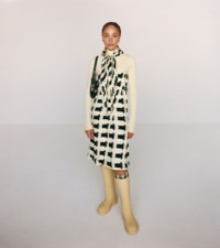 Modelo usando um vestido com estampa de pato em Sherbet e Ivy, com meias em mescla de lã xadrez e bolsa de ombro Chess de couro com logotipo B bordado.