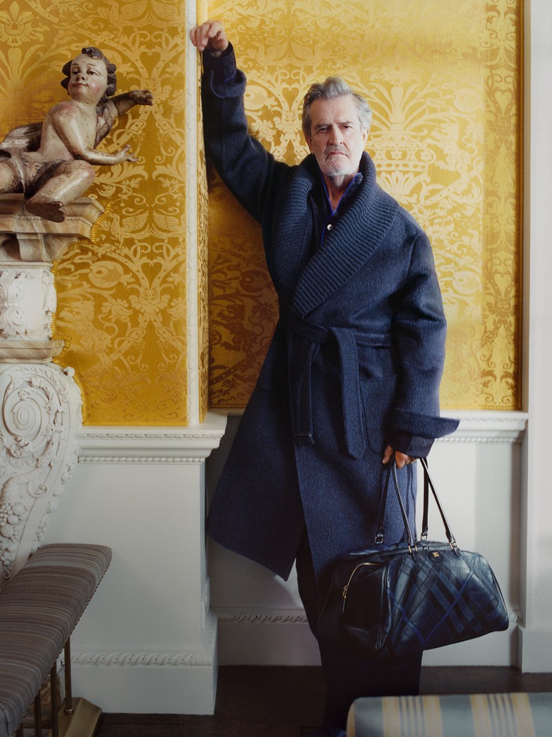 Aufnahme von Rupert Evertt in Burberry-Oberbekleidung mit einer Burberry-Reisetasche mit geprägtem Karomuster in der Hand