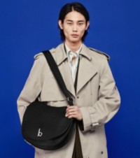 Modelo usando um trench coat e segurando uma bolsa satchel Rocking Horse grande e preta