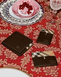 Mesa de comedor con dos platos y tres carteras y tarjeteros Burberry color negro en el centro
