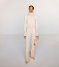 Model wearing the Prince of Wales jacquard turtleneck top and track pants in cameo and sherbet, paired with mules in daffodil.