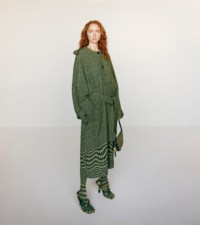 Modella che indossa cappotto in jacquard di lana con motivo a quadri Principe di Galles in ivy abbinato a borsa Shield e sandali Pool in spugna ivy. 