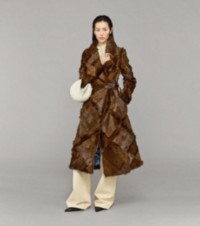 Modella con cappotto patchwork in shearling, camicia Burberry Check, chino e borsa Knight Junior