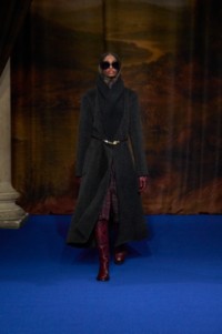 Ashley Fletcher wearing wool cashmere shawl collar coat in pier melange, wool blend rollneck sweater in mahogany red, check wool blend skirt in drab purple and night black, leather cavalier boots in fig purple, paired with metal and acetate sunglasses in black.