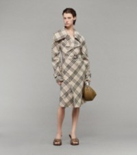 Modelo que luce vestido estilo trench coat con motivo a cuadros Burberry Check, sandalias Coast y bolso Knight Arc en piel