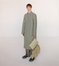 Modello che indossa car coat e pantaloni con motivo pied-de-poule in ivy, abbinati a borsa Muff in pelle e shearling color hunter. 