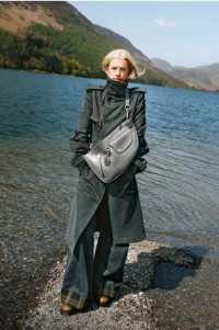 Model in Burberry-Trenchcoat mit mittelgroßer gestrickter Henkeltasche in Check in der Farbe Lichen.