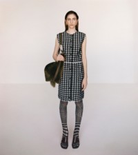 Model wearing the Houndstooth towelling viscose dress in black, styled with the Prince of Wales check tights in black and white.
