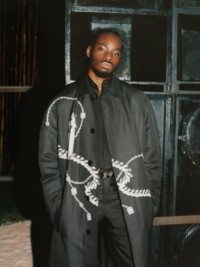 블랙 색상의 트렌치코트를 착용한 남성 모델