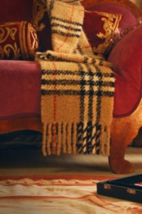 Écharpe Burberry Check en cachemire posée sur un fauteuil en velours rouge 