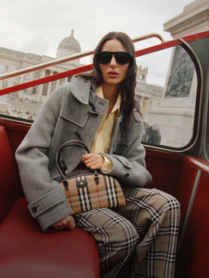 Model sat on London Red Bus, holding the Highlands Bowling Bag​ in colour Sand