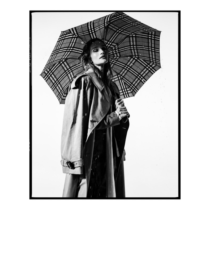 Aufnahme von Model Rosie Huntington-Whitely im langen Burberry-Trenchcoat „Castleford“ mit Schirm im Burberry Check-Karomuster in der Hand.