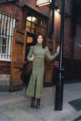 Model in einem Oberteil aus einer Wollmischung in einem Jacquard-gewebten Prince of Wales-Karomuster in den Farben Sherbet und Ivy mit hohem Kragen