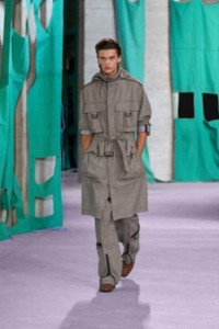 Model wearing Prince of Wales check tri-layer wool blend field coat and wool cargo trousers in log and plaster.